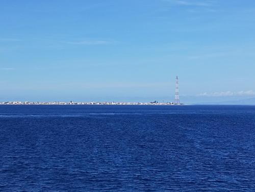 a large body of water with a lighthouse in the distance at La camera nel villaggio in Messina
