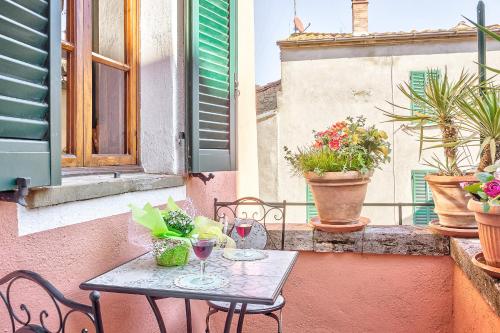 a table and chairs on a balcony with potted plants at Biancalana Apartment in Sinalunga