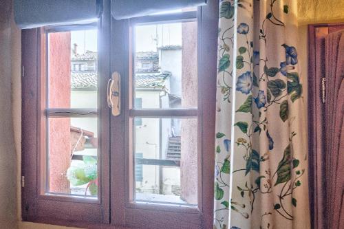 a glass door with a window with a curtain at Biancalana Apartment in Sinalunga