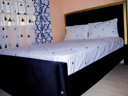 a bed with a black frame and white sheets at Arctic tern homes in Embu