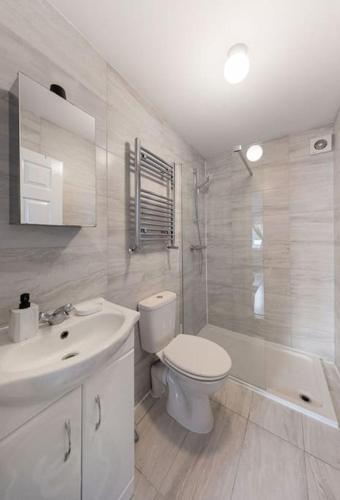 a white bathroom with a toilet and a sink at Parkside Haven, Modern 2-Bed Flat with Ensuites, Free Parking & Self Check-In in Perivale