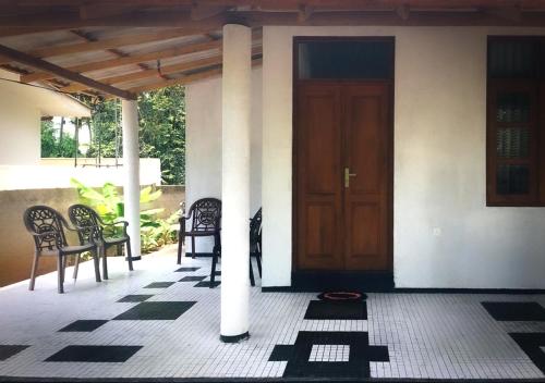 a front porch with a wooden door and chairs at Cloudy Rest Mirissa in Mirissa