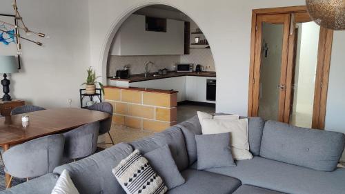 a living room with a blue couch and a kitchen at Marsaxlokk Sea View in Marsaxlokk