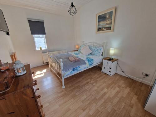 a small bedroom with a bed and a wooden floor at The Speak Easy Cottage Multyfarnham 0876682090 in Multyfarnham