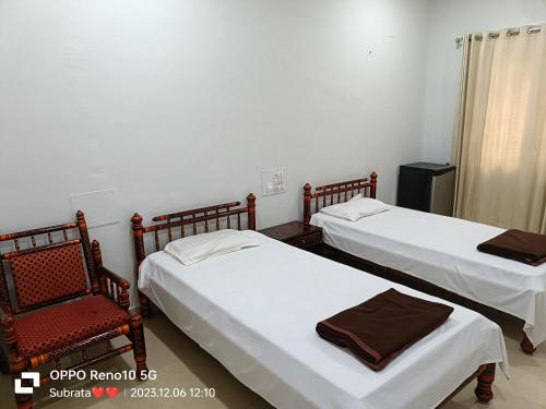 2 Betten und ein Stuhl in einem Zimmer in der Unterkunft Iskcon temple vadodara in Vadodara