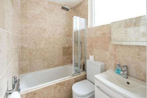 a bathroom with a toilet and a tub and a sink at Charming 1-Bed Apartment in London in London
