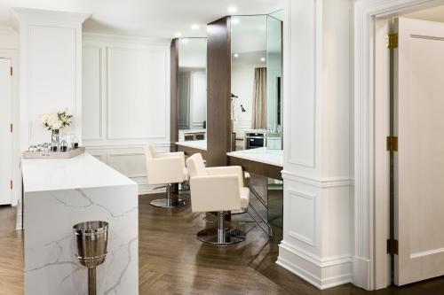 Habitación con baño blanco con encimera y sillas. en The Chateau Grande Hotel, en East Brunswick