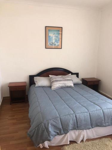 1 dormitorio con 1 cama azul y 2 mesitas de noche en San Sebastian en Concepción