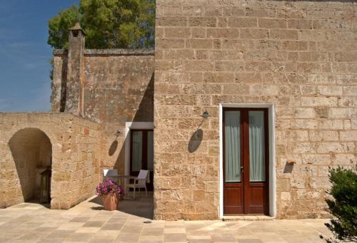 um edifício de tijolos com uma porta e um pátio em Masseria Corda Di Lana Hotel & Resort em Torre Lapillo