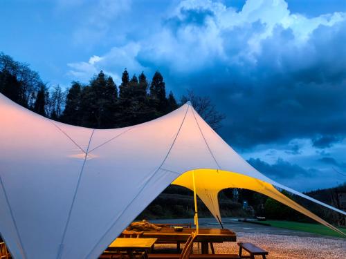 une grande tente blanche avec une table de pique-nique dans l'établissement Zhangjiajie National Forest Park Camping, à Zhangjiajie