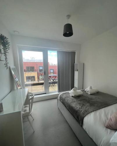 1 dormitorio con cama, mesa y ventana en Private room in London with balcony en Woolwich