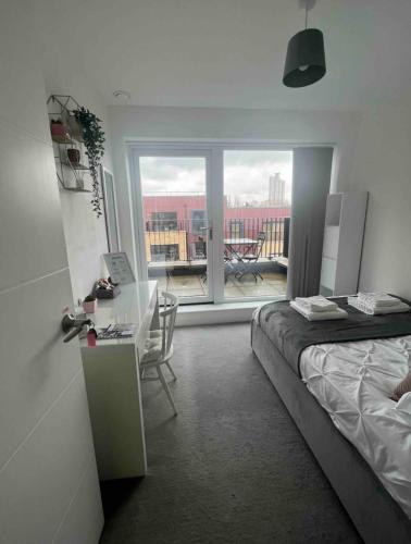 a bedroom with a bed and a desk and a balcony at Private room in London with balcony in Woolwich