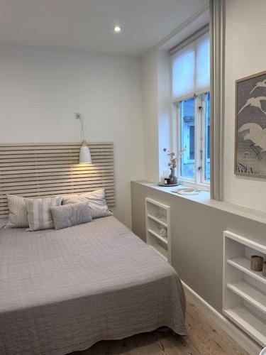 a white bedroom with a bed and a window at City center apartment w/ large private balcony in Aalborg