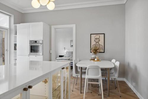 una cocina con armarios blancos y una mesa y sillas blancas. en City center apartment w/ large private balcony, en Aalborg