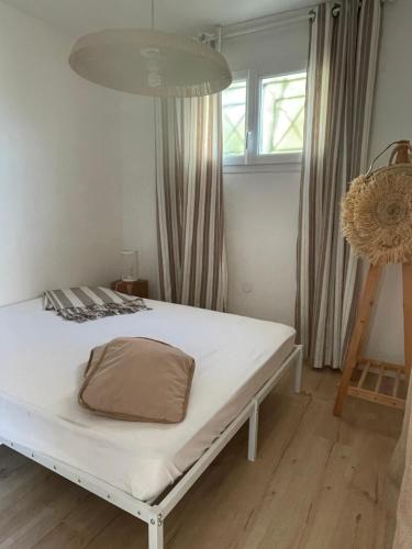 a white bed with a pillow on it in a room at T2 Dans le vent Gruissan bord de mer in Gruissan
