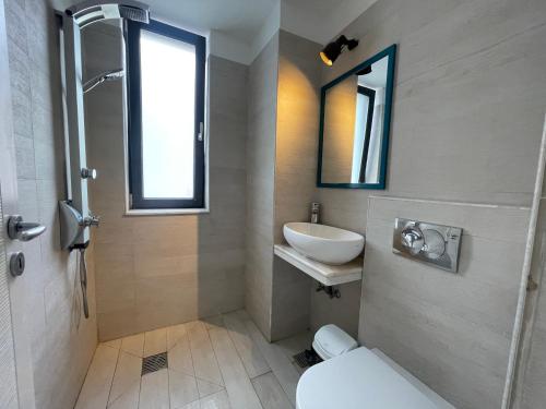 ein Badezimmer mit einem Waschbecken, einem WC und einem Spiegel in der Unterkunft BLUEMARINA SUMMERLAND SEA VIEW STUDIOS in Mamaia