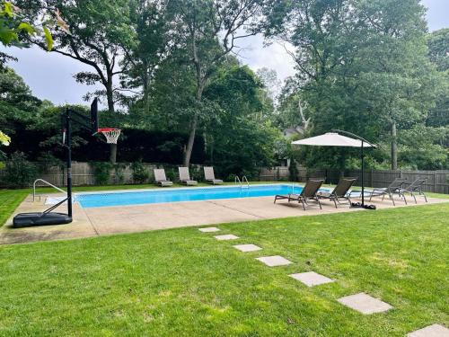 a pool with chairs and a basketball hoop and an umbrella at PRIVATE ROOM, BATHROOM & ENTRANCE DOOR w/ POOL in East Hampton