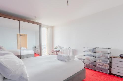 a white bedroom with two beds and a mirror at Quirky 1BD Flat wGym & City Views Dalston! in London