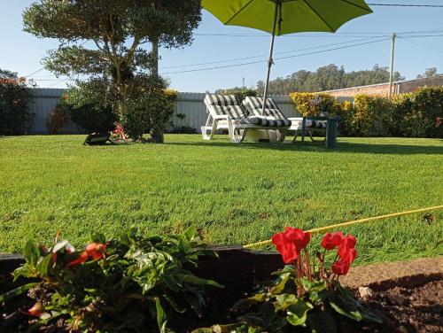 a garden with two chairs and an umbrella and flowers at TERRENO DAS MIMOSAS in Aveiro