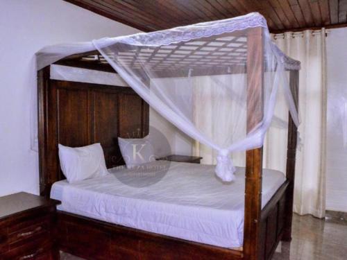 a bedroom with a canopy bed with white sheets at THE KEZA HOTEL near Kigali international airport. in Kigali