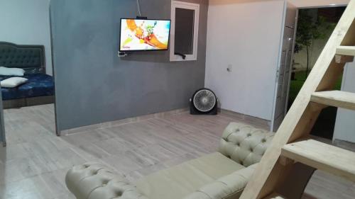 sala de estar con sofá y TV en la pared en Mi Quincho Cañuelas en Cañuelas