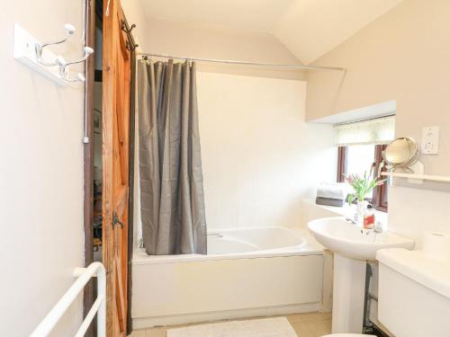 a bathroom with a tub and a sink at Dove Cottage in Leek
