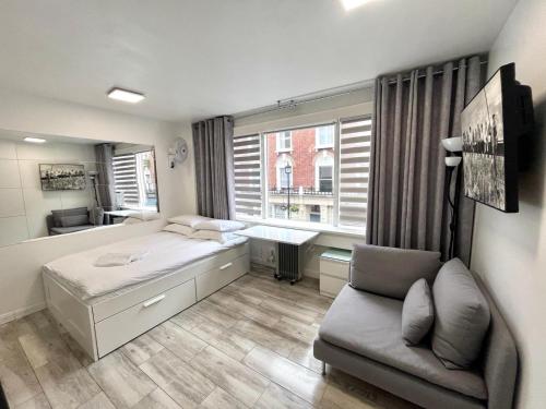 ロンドンにあるアパートメンツ クレイヴン テラスのベッド1台、ソファ、窓が備わる客室です。