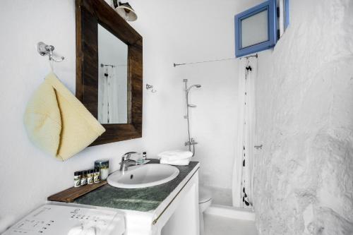 a white bathroom with a sink and a mirror at La Casa del Pastore in Serifos Chora