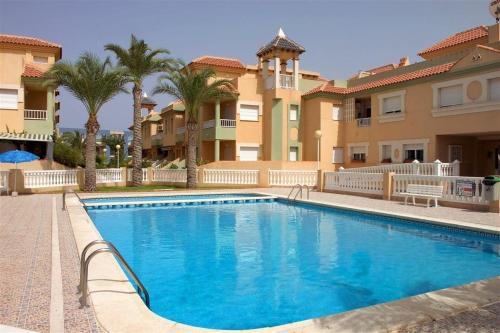 a swimming pool in front of a building with palm trees at Apartamentos Turísticos Puerto Tomás Maestre in La Manga del Mar Menor