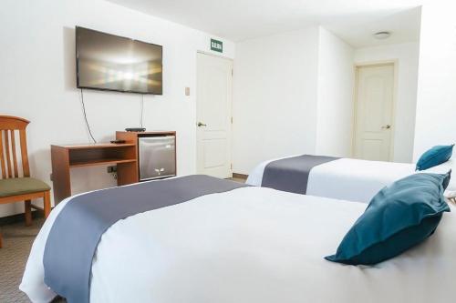 Habitación de hotel con 2 camas y escritorio en Hotel Asturias, en Arequipa