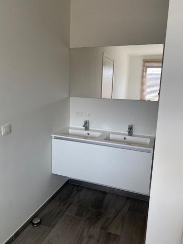 Baño blanco con lavabo y espejo en Residentie Nivaria Zeebrugge, appartement met 1 slaapkamer aan de jachthaven, en Zeebrugge