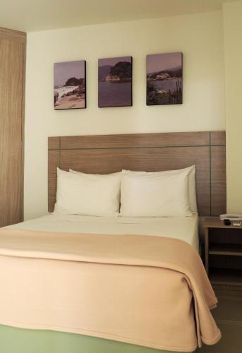 a bedroom with a bed with four pictures on the wall at Hotel Zamay Gaira in Santa Marta