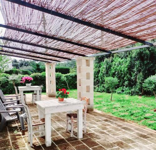 a white table and chairs under a wooden pergola at La dimora di nonna Giuliana in Ostuni