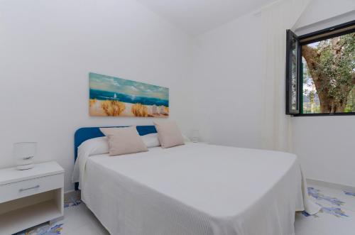 a white bedroom with a bed and a window at Le Case di Chri in Mattinata