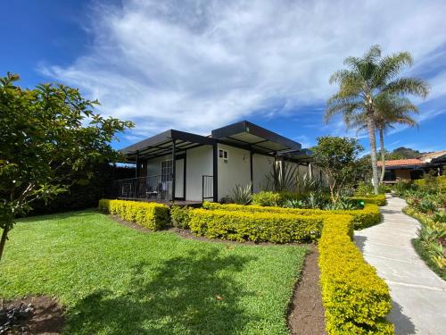 a house with a garden and a palm tree at Hotel & Golf Isak Aeropuerto in Rionegro
