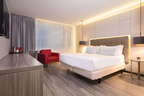 a hotel room with a bed and a red chair at NH Collection Medellin Royal in Medellín