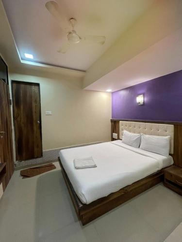 a bedroom with a large white bed with a purple wall at Hotel Golden Park Near NESCO in Mumbai