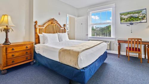 a bedroom with a bed and a desk and a window at Crystal Bay Historic Hotel in St Petersburg