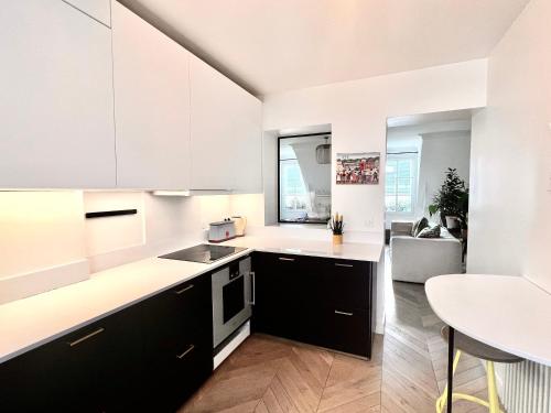 une cuisine avec des armoires blanches et noires et une table dans l'établissement Appartement cosy à Paris 130 m² avec projecteur !, à Paris