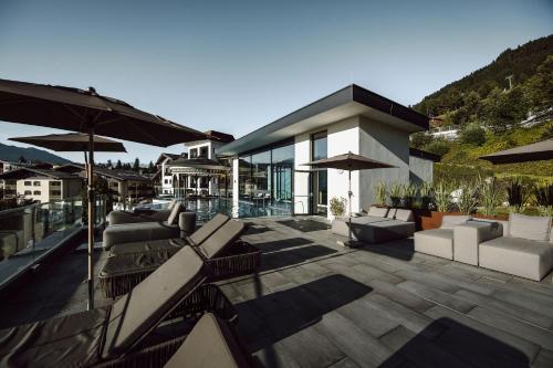 a patio with chairs and umbrellas on a house at Alpina Alpendorf in Sankt Johann im Pongau