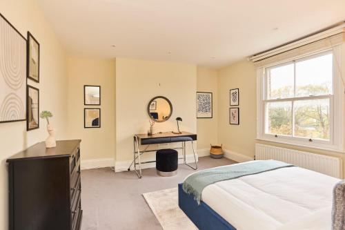 a bedroom with a bed and a desk and a window at The Peckham Hideaway - Bright 3BDR Flat in London