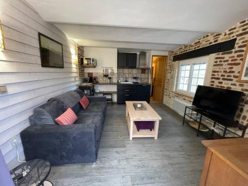 ein Wohnzimmer mit einem Sofa und einem Tisch in der Unterkunft Le paddock deauvillais in Deauville