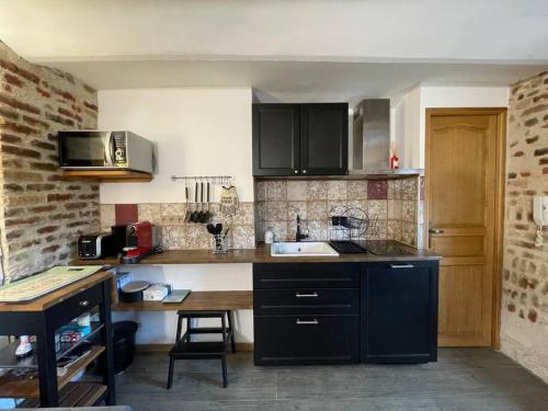 eine Küche mit schwarzen Schränken und einer Arbeitsplatte in der Unterkunft Le paddock deauvillais in Deauville