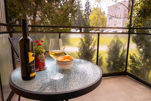 Apartment City Cat في Križevci: زجاجة من النبيذ وكأس على طاولة على شرفة