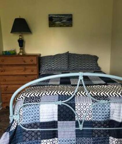 a bed with a black and white blanket and a dresser at Experience Tranquility Cricket Field Offers Charming Retreat in Twillingatate in Twillingate