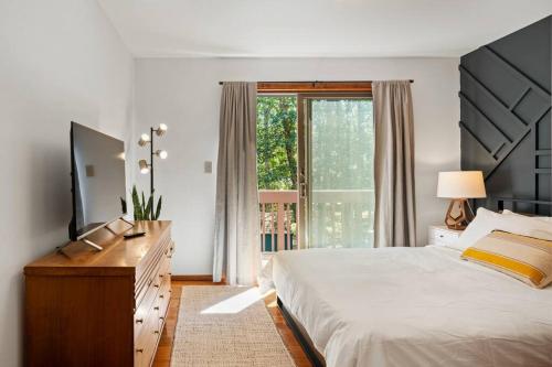1 dormitorio con 1 cama, vestidor y ventana en The Green Forest Retreat - Kayak, Hot Tub, Sauna en East Stroudsburg