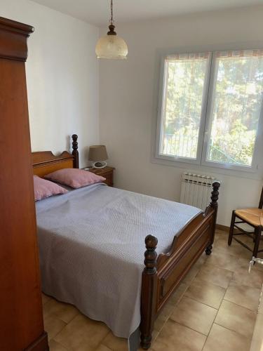 ein Schlafzimmer mit einem Bett und zwei Fenstern in der Unterkunft La Pinède in Sanary-sur-Mer