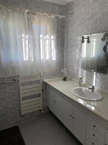 ein weißes Badezimmer mit einem Waschbecken und einem Spiegel in der Unterkunft La Pinède in Sanary-sur-Mer