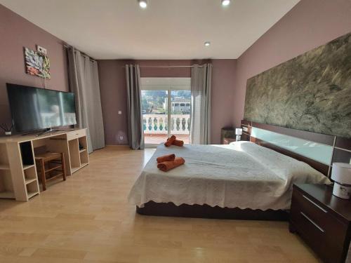 1 dormitorio con 1 cama grande y TV en Costa Brava Suites Villa Cèsar, en Calonge