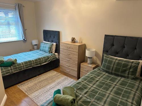 a bedroom with two beds and a chair and a dresser at Acorns in Holywell